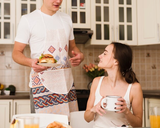 Romantique jeune homme servant le petit déjeuner avec femme