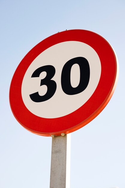 Rond 30 signe de limite de vitesse contre le ciel bleu