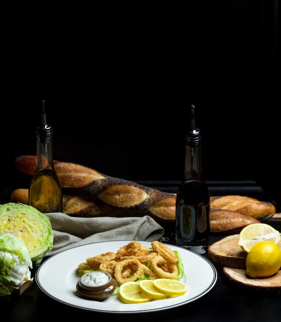 Photo gratuite rondelles d'oignon en pâte avec sauce et tranches de citron