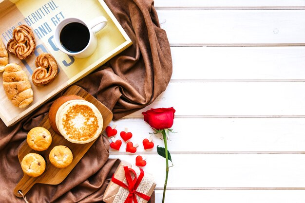 Rose et cadeau près de la pâtisserie et du café