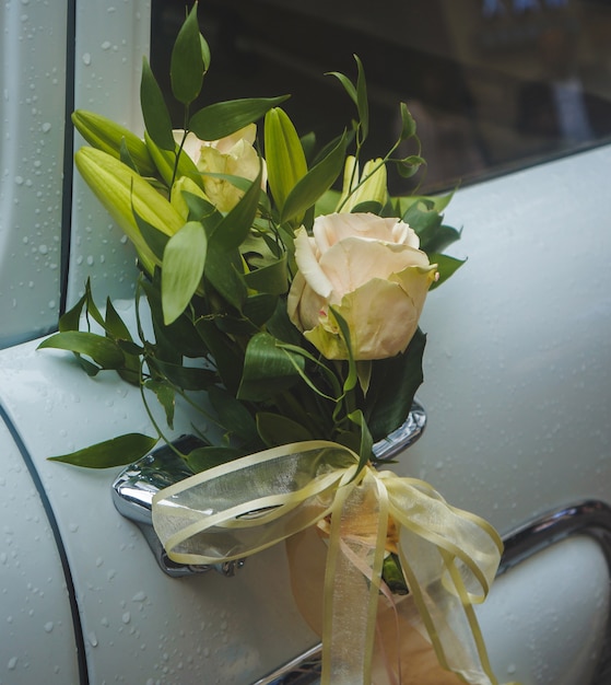 Une rose jaune avec des fleurs décoratives dans le manche d'une voiture de luxe blanche