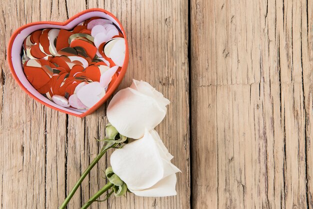 Roses avec des coeurs de papier dans une boîte