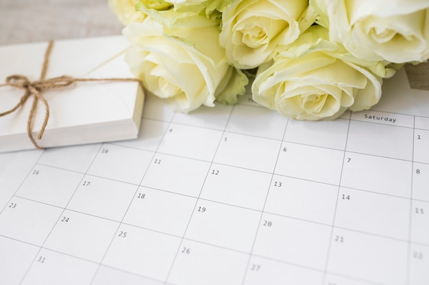 Photo gratuite roses jaunes et pile d'enveloppes sur calendrier