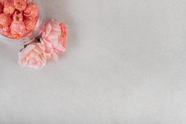 Roses par un petit bol de pop-corn rouge sur table en marbre.