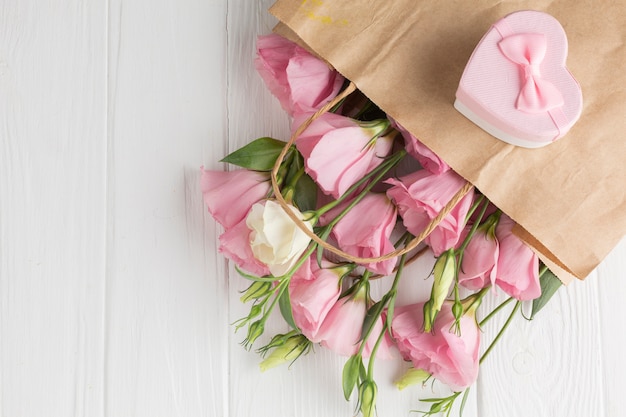 Roses roses dans un sac en papier avec une boîte cadeau