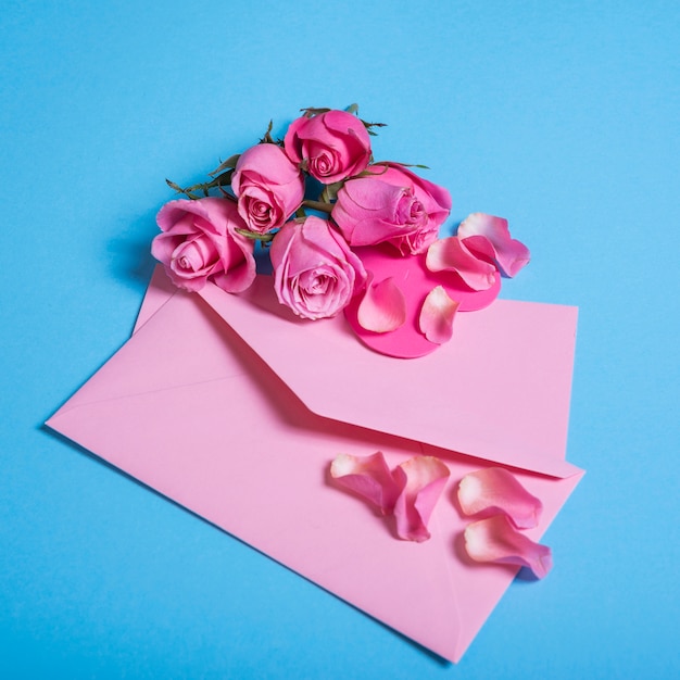 Roses roses avec enveloppe sur la table bleue