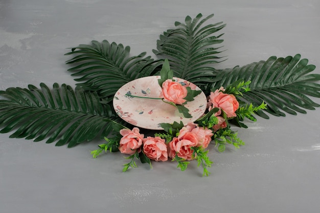Roses roses avec des feuilles vertes et une plaque sur une surface grise