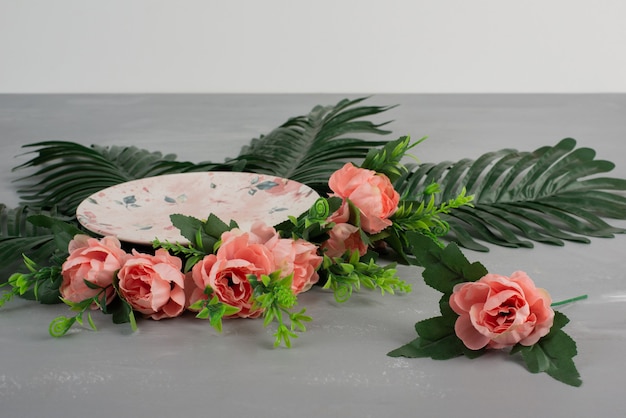Roses roses avec des feuilles vertes et une plaque sur une surface grise.