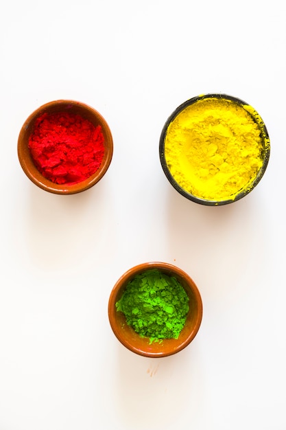 Photo gratuite rouge; poudre de couleur holi jaune et verte dans les bols sur fond blanc