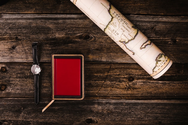 Roulé de carte, agenda et montre au poignet sur table en bois