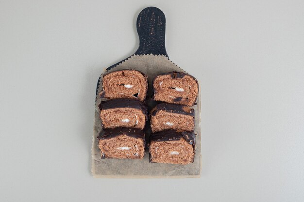 Rouleau de chocolat sucré en tranches sur une planche de bois.