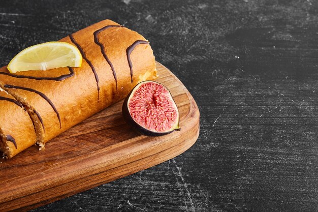 Rouleau éponge fourré au chocolat sur une planche de bois.