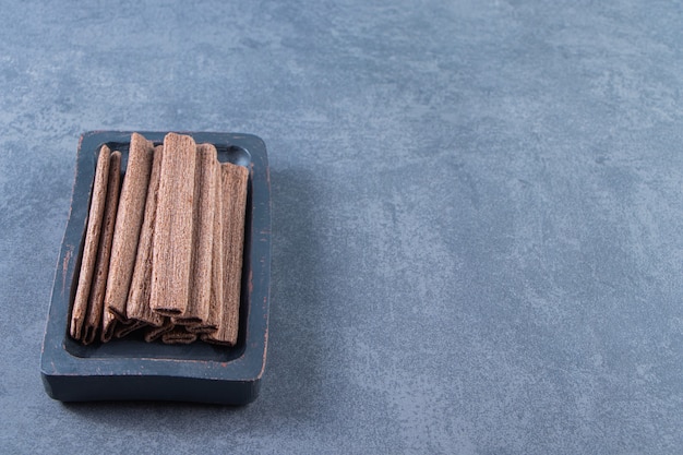 Rouleau de gaufrette au chocolat savoureux dans une assiette en bois, sur fond de marbre.