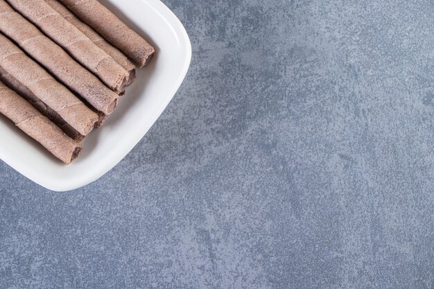 Rouleau de gaufrettes au chocolat délicieux dans un bol sur la surface en marbre