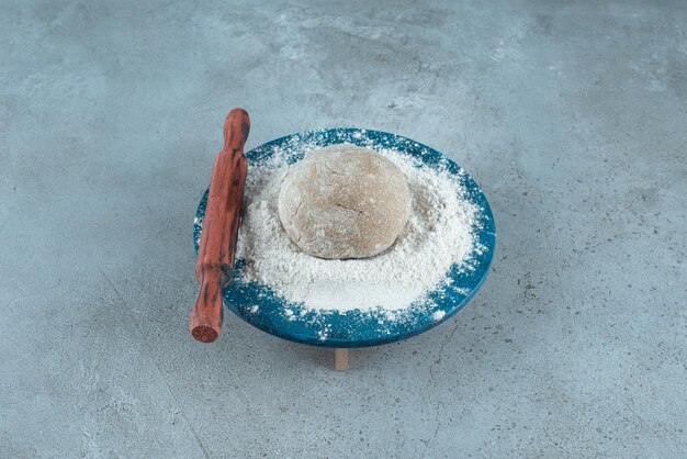 Rouleau de pâte avec de la farine sur une plaque en bois avec un rouleau à pâtisserie.