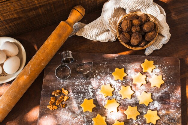 Rouleau à pâtisserie et emporte-pièce près des biscuits crus et des ingrédients