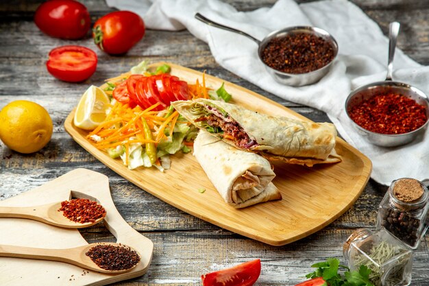 Rouleau de poulet sur planche de bois tomate citron sumakh vue latérale