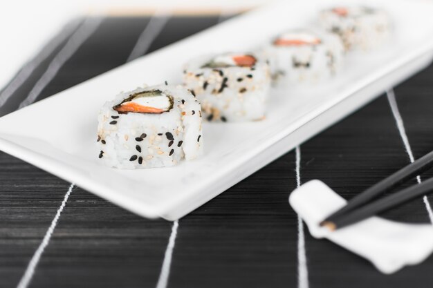 Rouleau de sushi sur un plateau blanc avec des baguettes