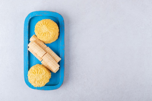 Rouleaux de gaufres et biscuits sur la plaque de bois, le marbre.