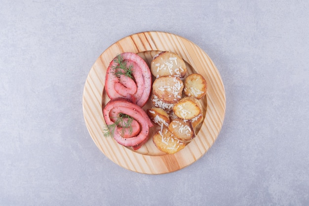 Rouleaux de jambon et pommes de terre frites sur plaque de bois.