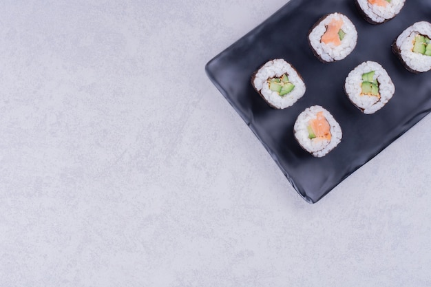 Rouleaux De Maki Saké Dans Un Plateau En Céramique Noire