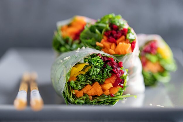 Rouleaux de papier de riz végétalien aux légumes et au sésame servis sur une assiette prête à manger