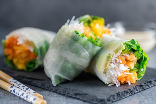 Rouleaux de papier de riz végétalien aux légumes et au sésame servis sur une assiette prête à manger