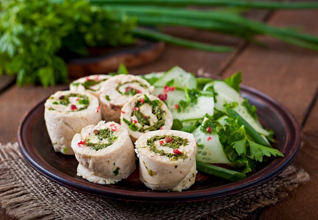 Rouleaux de poulet cuit à la vapeur avec des légumes verts et une salade de légumes frais sur une plaque brune