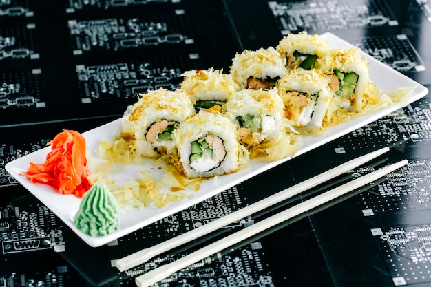 Rouleaux de sushi au saumon cuit et concombre servi avec du gingembre et du wasabi