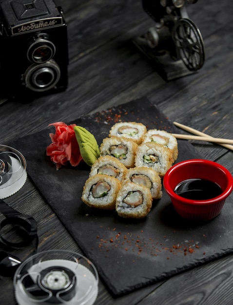 Rouleaux de sushi, californie chaude avec sauce et gingembre rouge sur un plateau en pierre