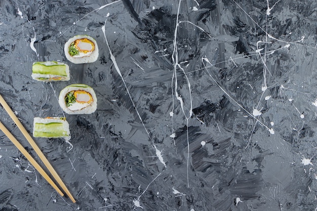 Rouleaux de sushi dragon vert placés sur fond de marbre.