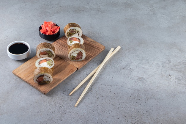 Rouleaux de sushi, sauce soja, wasabi et gingembre mariné sur fond de pierre.