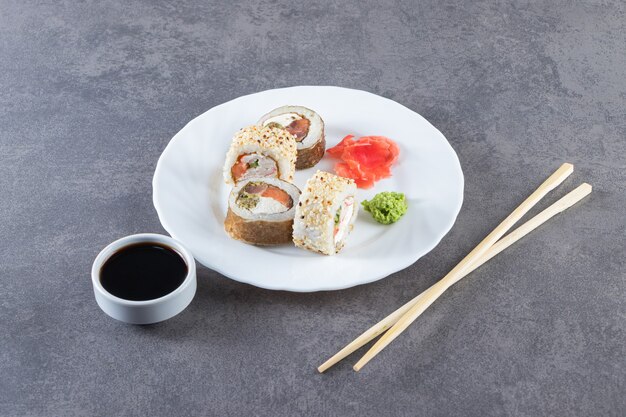 Rouleaux de sushi, sauce soja, wasabi et gingembre mariné sur la surface de la pierre.