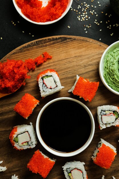 Rouleaux de sushi servis sur plaque en bois avec vue de dessus des ingrédients classiques