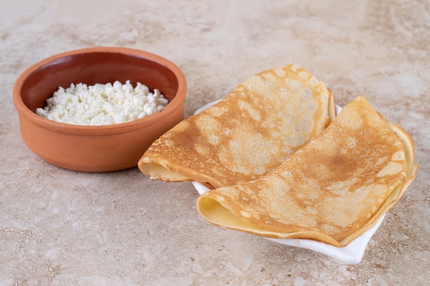 Rouler les crêpes avec du fromage cottage et un bol en argile