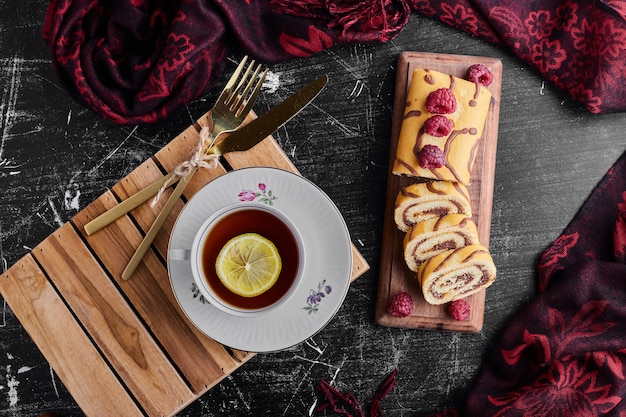 Rouler le gâteau avec du chocolat et des baies et une tasse de thé.