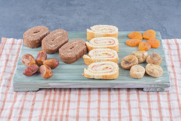 Rouler le gâteau et les fruits secs sur le plateau, sur le fond de marbre.