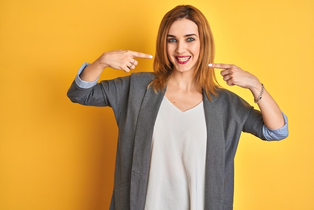 Rousse caucasienne femme d'affaires sur fond jaune isolé souriant joyeux montrant et pointant avec les doigts les dents et la bouche concept de santé dentaire