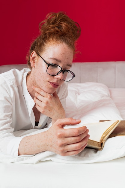 Photo gratuite rousse vue de face en lecture lit