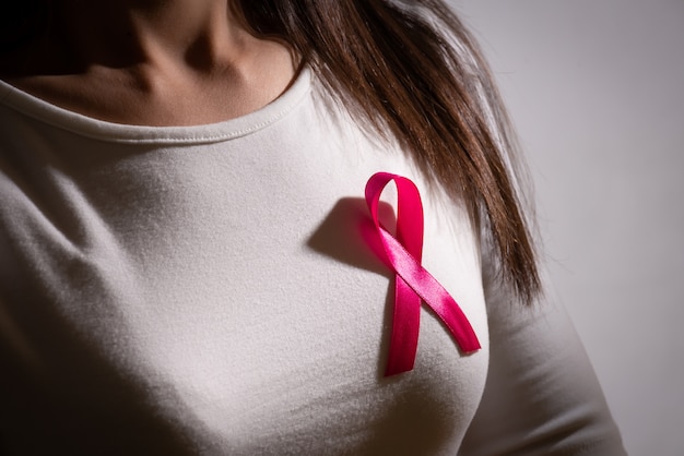 Ruban d'insigne rose sur la poitrine de la femme pour soutenir la cause du cancer du sein.
