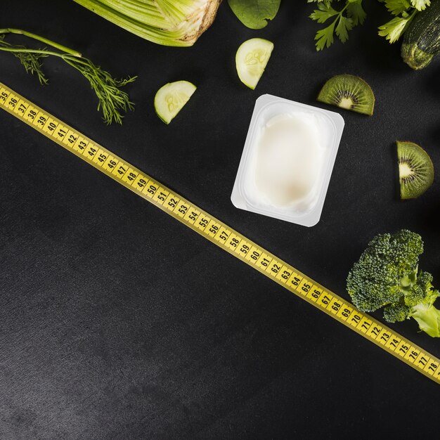 Ruban à mesurer et divers aliments verts sains sur fond noir