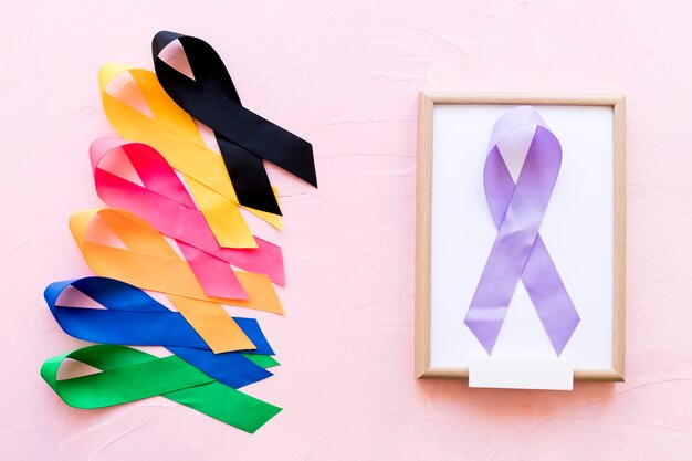 Ruban violet sur un cadre en bois blanc avec la rangée de ruban de conscience coloré