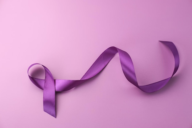 Ruban violet comme symbole de la journée mondiale du cancer sur l'espace de copie d'arrière-plan de couleur pourpre