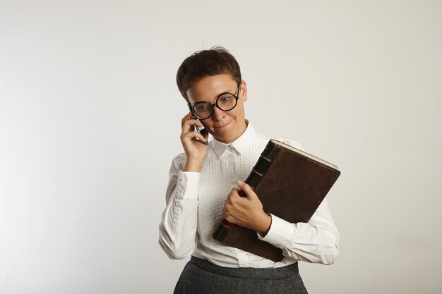 S'ennuyer à la femme enseignante écoute patiemment son téléphone mobile isolé sur blanc