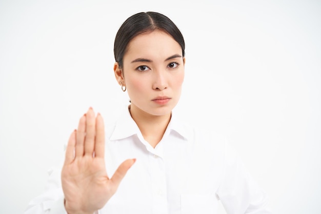 Photo gratuite s'il vous plaît, arrêtez suffisamment de femmes d'affaires asiatiques sérieuses montrant un geste de la main étendu désapprouver