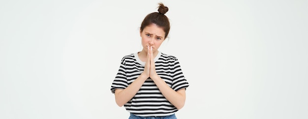 Photo gratuite s'il vous plaît, une jeune femme demande de l'aide vous supplie de vous tenir la main en priant, plaidant isolée contre le blanc