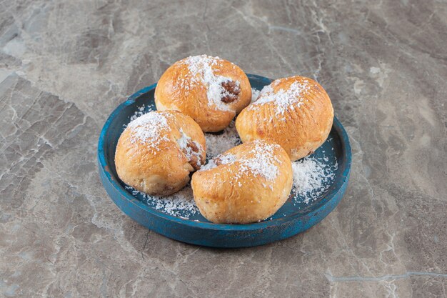 Sablés au miel avec flocons de noix de coco sur une plaque en bois sur marbre.