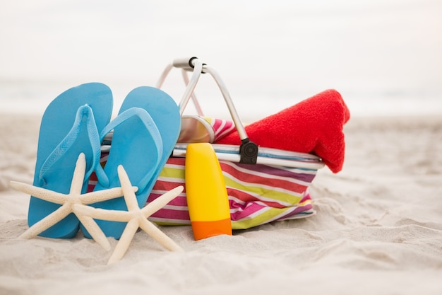 Photo gratuite sac et accessoires de plage conservés sur le sable