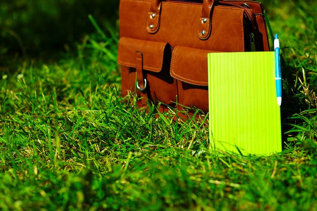 Sac en cuir marron rétro homme et ordinateur portable dans l'herbe d'été coloré lumineux dans le parc