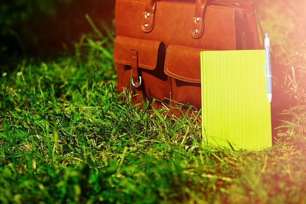 Photo gratuite sac en cuir marron rétro homme et ordinateur portable dans l'herbe d'été coloré lumineux dans le parc